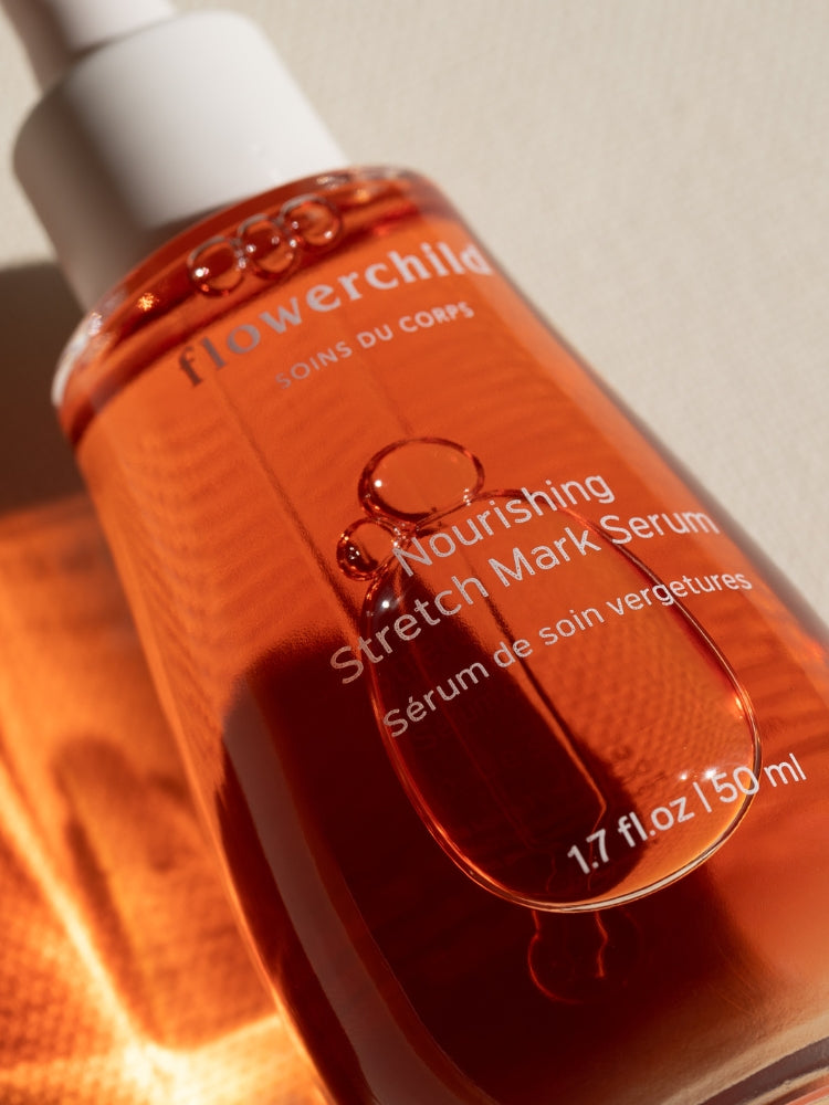 Gros plan du sérum nourrissant vergetures Flowerchild dans un flacon en verre ambré, capturant la lumière naturelle pour mettre en valeur sa texture riche.