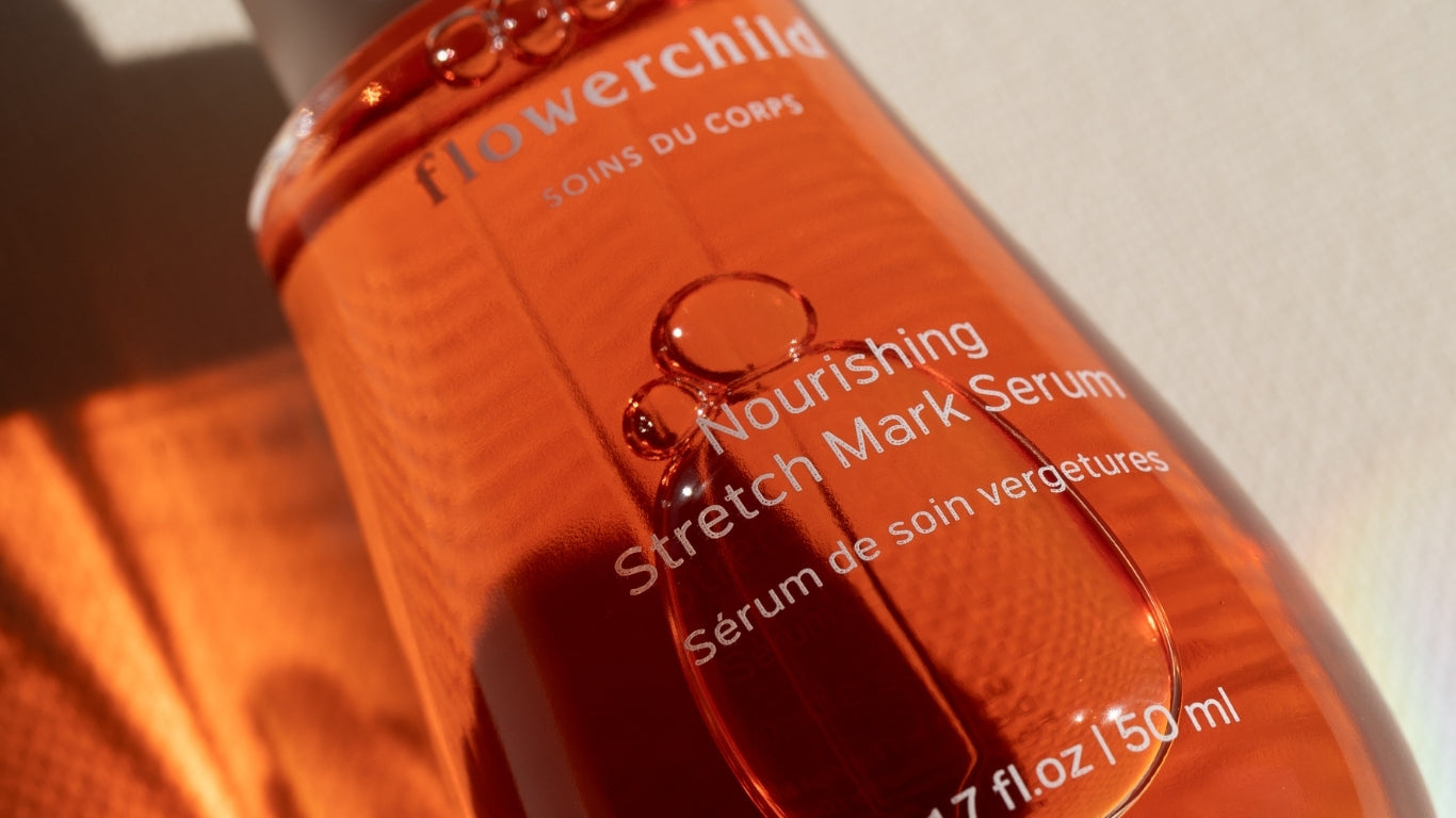 Gros plan du sérum nourrissant vergetures Flowerchild dans un flacon en verre ambré, capturant la lumière naturelle pour mettre en valeur sa texture riche.