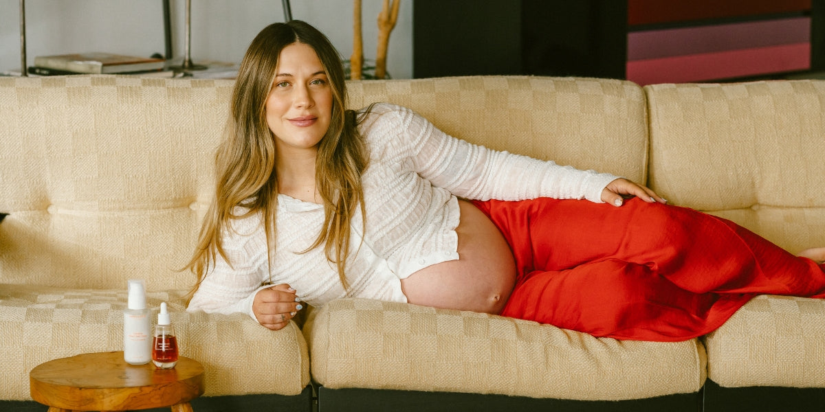 Une femme enceinte sereine posant sur un canapé avec le Duo Vergetures de Flowerchild Soins du Corps à ses côtés, illustrant une routine de beauté naturelle, sécuritaire et transparente pour les futures mamans au Canada.