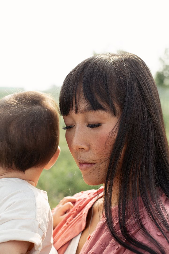 Mère portant son bébé dans un champ en été, moment tendre et naturel