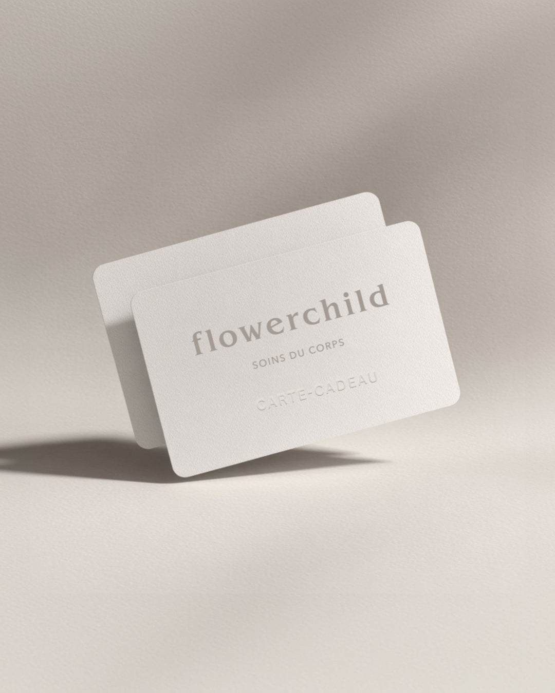 Carte-cadeau Flowerchild Soins du Corps en papier texturé beige, avec logo embossé, pour offrir des soins naturels de maternité et de bien-être aux mamans, marque québécoise de skincare.